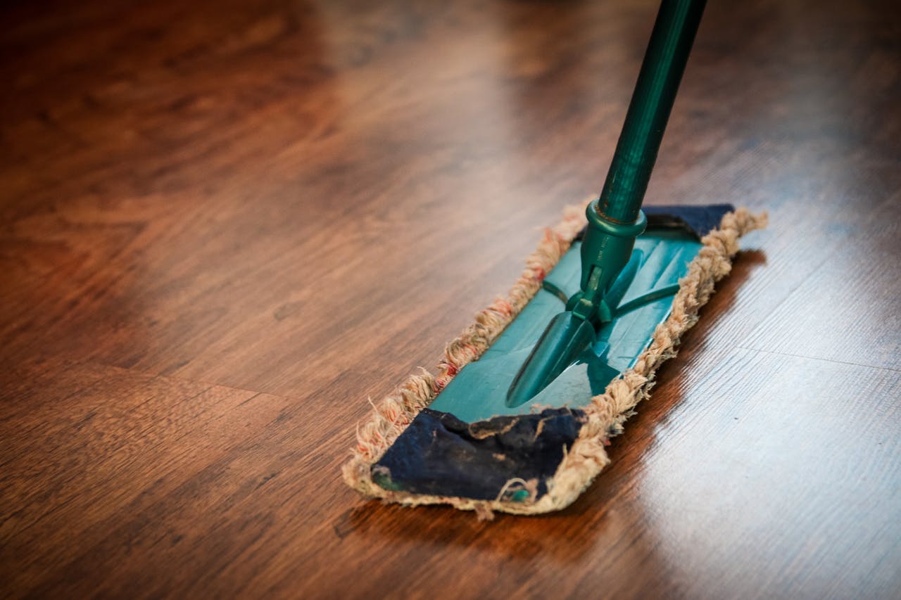 about-img-01 A detailed view of a mop cleaning a wooden floor, showing texture and pattern.