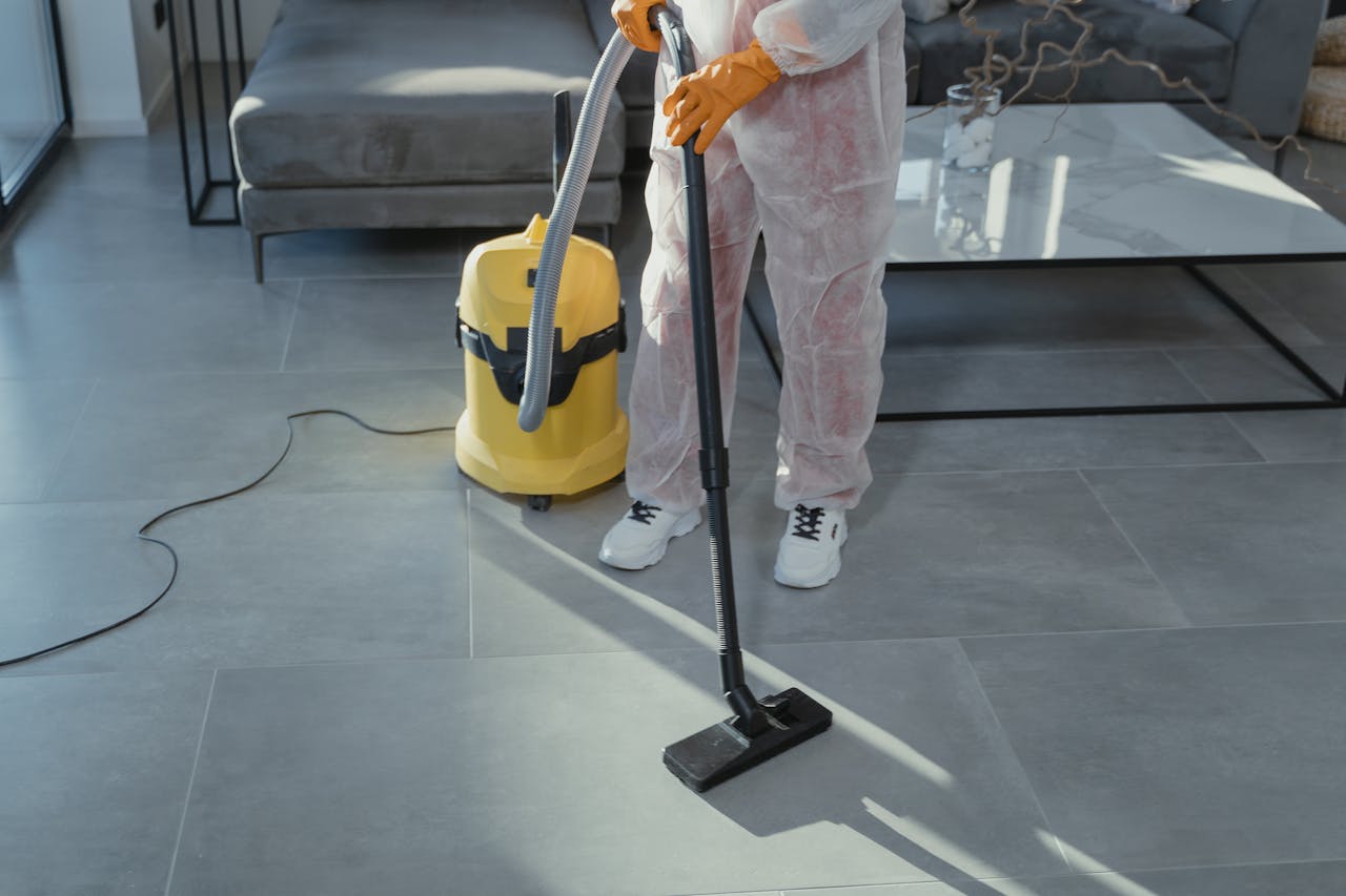 home-img A professional cleaner in protective gear vacuuming the floor in a modern living room.